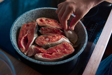 a man roasts fish in a pan on the stove