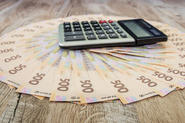 many 500 hryvnia and a calculator on a wooden background. Business concept.nicely laid out money on black.