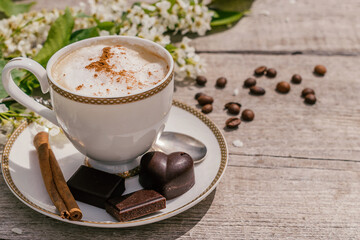 Сup of coffee and homemade chocolate sweets on a wooden background.Coffee beans, white flowers and cinnamon sticks adorn the composition.Сoncept of healthy food and healthy desserts.Copy space