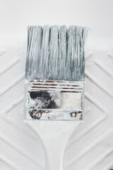 DIY and home improvement, close-up of paint tray with white glossy paint and paint brush