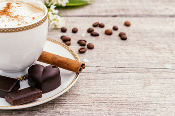 Сup of coffee and homemade chocolate sweets on a wooden background.Coffee beans, white flowers and cinnamon sticks adorn the composition.Сoncept of healthy food and healthy desserts.Copy space