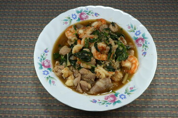 Spicy fried peeled shrimp, cutting chicken, chilly and basil with traditional sauce on the plate. Famous local street food in Thailand. Comfortable, quick and easy meal. Rush hour menu in Asia. 