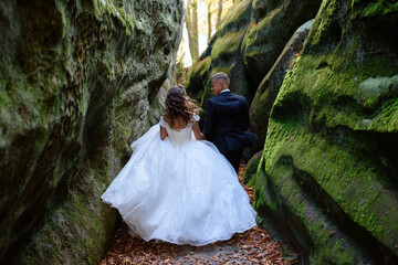 Bride and groom. A couple strolling among the narrow beautiful gorge. The gorge was overgrown with green moss. The newlyweds are spinning and running.