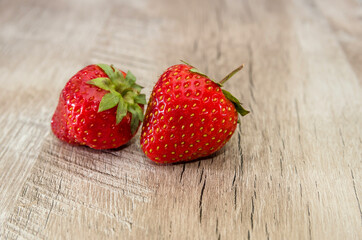 two ripe strawberries on a wooden background. Close-up.