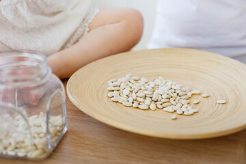 Cute little girl playing at home with eco-friendly wooden toys. The child has fun with the role playing kitchen and cooking game with grits beans