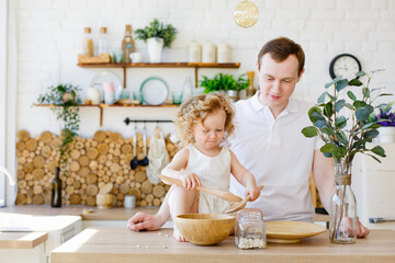 Father and daughter play with cereal in the kitchen. The concept of Montessori education. Together at home. Entertainment for the whole family.