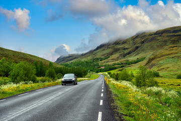 Highway roads and cars in the mountains and valleys in the summer There are wildflowers throughout the countryside in Iceland. Concept for holiday travel driving.