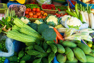 Fresh vegetables, fruits and greens on a counter in a street market