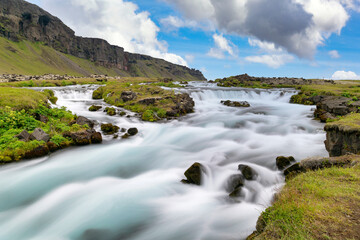 Mountains and beautiful streams in summer, with green grass and blue skies with beautiful clouds In the countryside in Iceland The picture is bright and refreshing, looks relaxed.