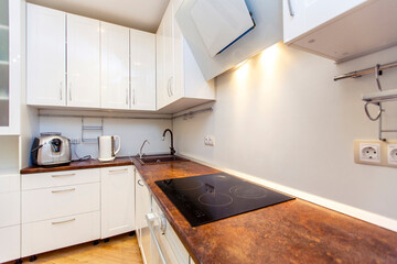 Modern white kitchen with beige countertops and kitchen appliances.
