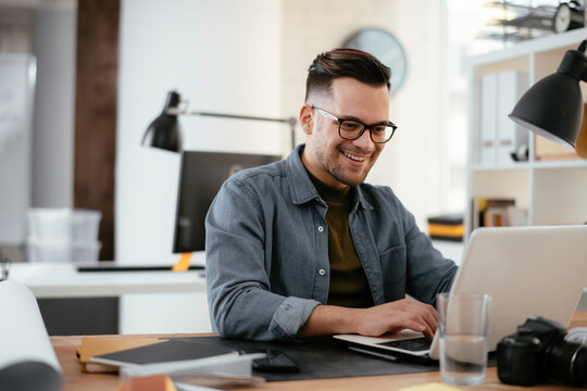 Young businessman using laptop in his office.  Handsome man working in office.	
