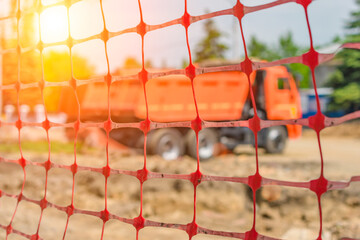 Fence net behind which is a truck at a construction site