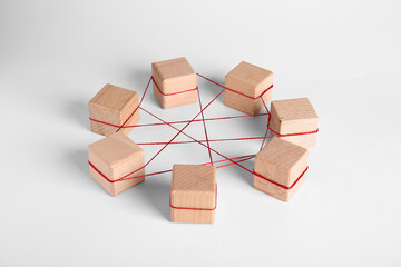 Wooden cubes tied with red thread on light background. Unity concept