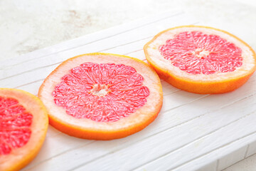 Board with fresh cut grapefruit on light background, closeup