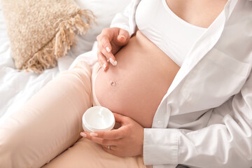 Beautiful pregnant woman with cream at home
