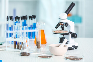 Samples of soil, microscope and glassware on table in laboratory