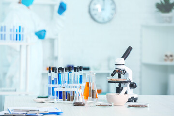 Samples of soil, microscope and glassware on table in laboratory