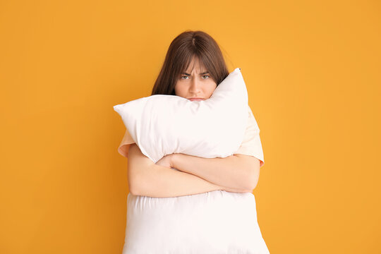 Tired woman with pillow on color background. Concept of sleep deprivation