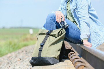 Female traveler with backpack sitting on railway tracks