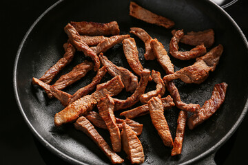 Frying pan with pieces of tasty beef meat on stove