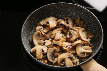 Frying pan with tasty mushrooms on stove