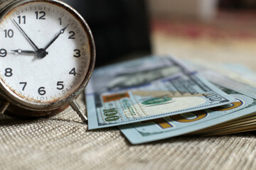 Time is money concept. Old alarm clock and a stack of banknotes. Selective focus.