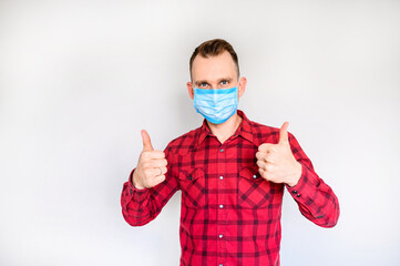 Viral protection. Guy in medical mask shows thumbs up gesture, isolated studio shot