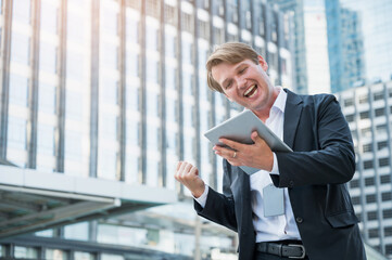 Young business man feeling happy celebration with hand and holding tablet