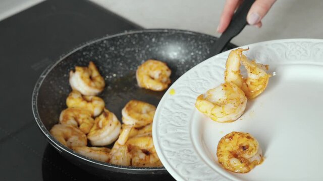 Girl puts juicy shrimp on a plate