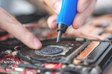 man cleans a laptop with a special tool for blowing dust cooling system. Repair and service laptops and PC Advertisement of repair service for electronics and devices