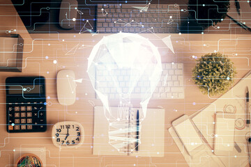 Bulb drawing over computer on the desktop background. Top view. Double exposure. Idea concept.