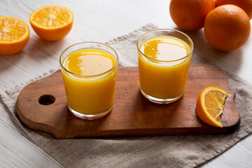 Healthy Orange Juice on a rustic board on a white wooden background, low angle view. Close-up.