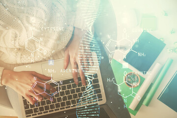 Double exposure of woman hands working on computer and DNA hologram drawing. Top View. Medical...