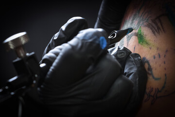 Female tattoo artist making tattoo on a men’s arm