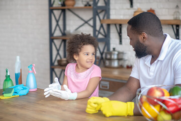 African american bearded man in yellow gloves talking to his cute kid