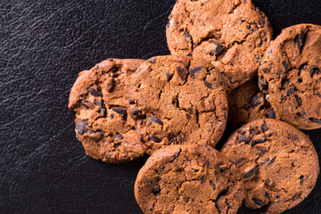 Appetizing chocolate chip cookies with slices of raisins on a black background.