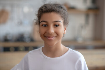 Cute curly-haired girl smiling and feeling happy