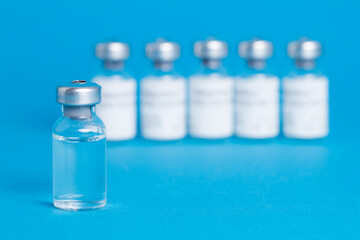 Closeup vaccine bottle on blue isolated background. Lack of coronovirus vaccine.