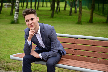 Portrait of a caucasian business man posing while sitting on a park bench. Photo taken in the spring.