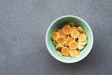 Freshly cooked pancake cereal in a bowl on grey concrete background.