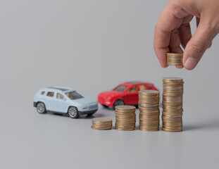 Mini car model with stack of golden coins and hand hilding coin,saving for car,loan and financial concept