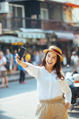 Happy young woman taking selfie on the street in the city