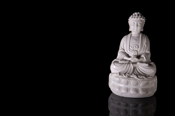 White Buddha on a black background with reflection