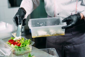 Food delivery in the restaurant. The chef prepares food in the restaurant and packs it in disposable dishes.