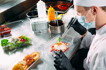 Food delivery in the restaurant. The chef prepares food in the restaurant and packs it in disposable dishes.