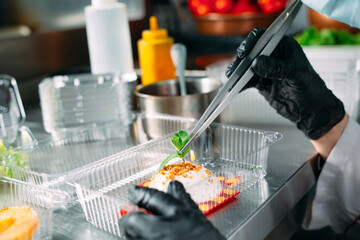 Food delivery in the restaurant. The chef prepares food in the restaurant and packs it in disposable dishes.