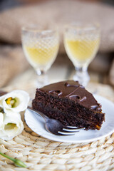 A slice of homemade chocolate cake with glass of apricot liquor.