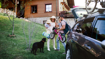 Family with two small children and dog going on cycling trip in countryside. - obrazy, fototapety, plakaty