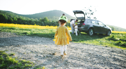 Rear view os small girl with family going on cycling trip in countryside.