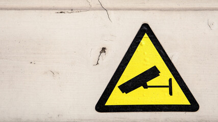 Yellow security camera sticker. Painted wooden facade. Procedures and compliance with regulations
